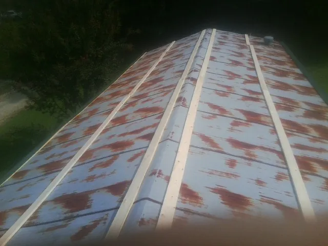 Rusted metal roof panels with new wood purlins before replacement — Storm Damage Roof Repair in North Sandwich by Roofing Brothers