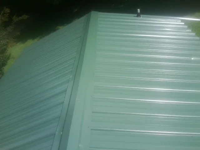 New green metal panels meeting at the ridge of a roof — Flat Roof Repair work by our crew in North Sandwich