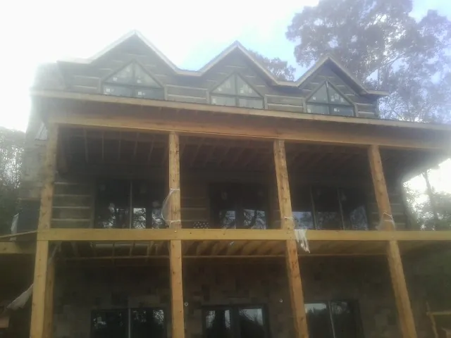 Dormers and porch framing on a large log home under construction — Roof Coating work by our crew in North Sandwich