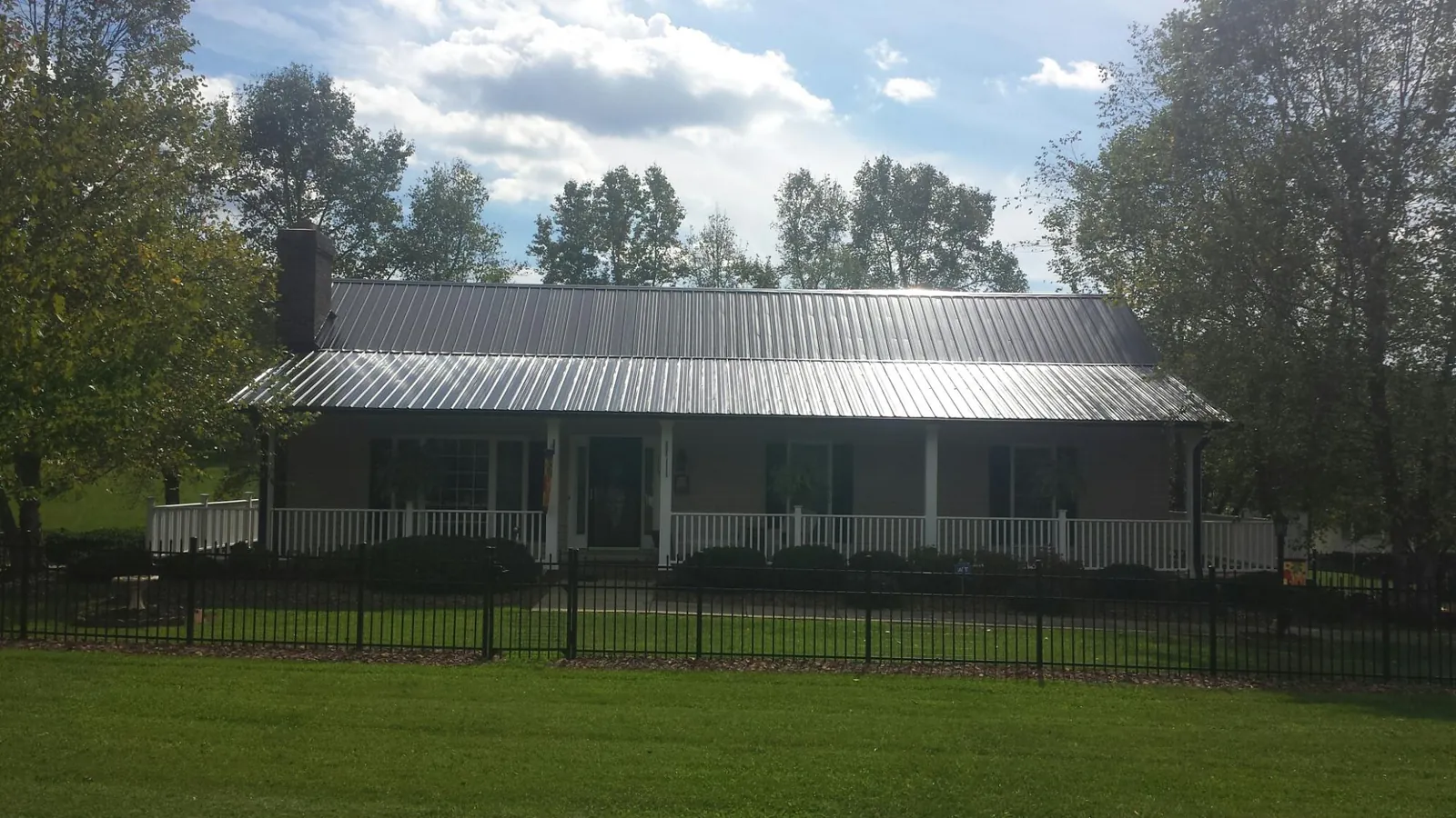 Gray metal roof on a brick ranch with a full width front porch — Gutter Guard Installation work by our crew in North Sandwich