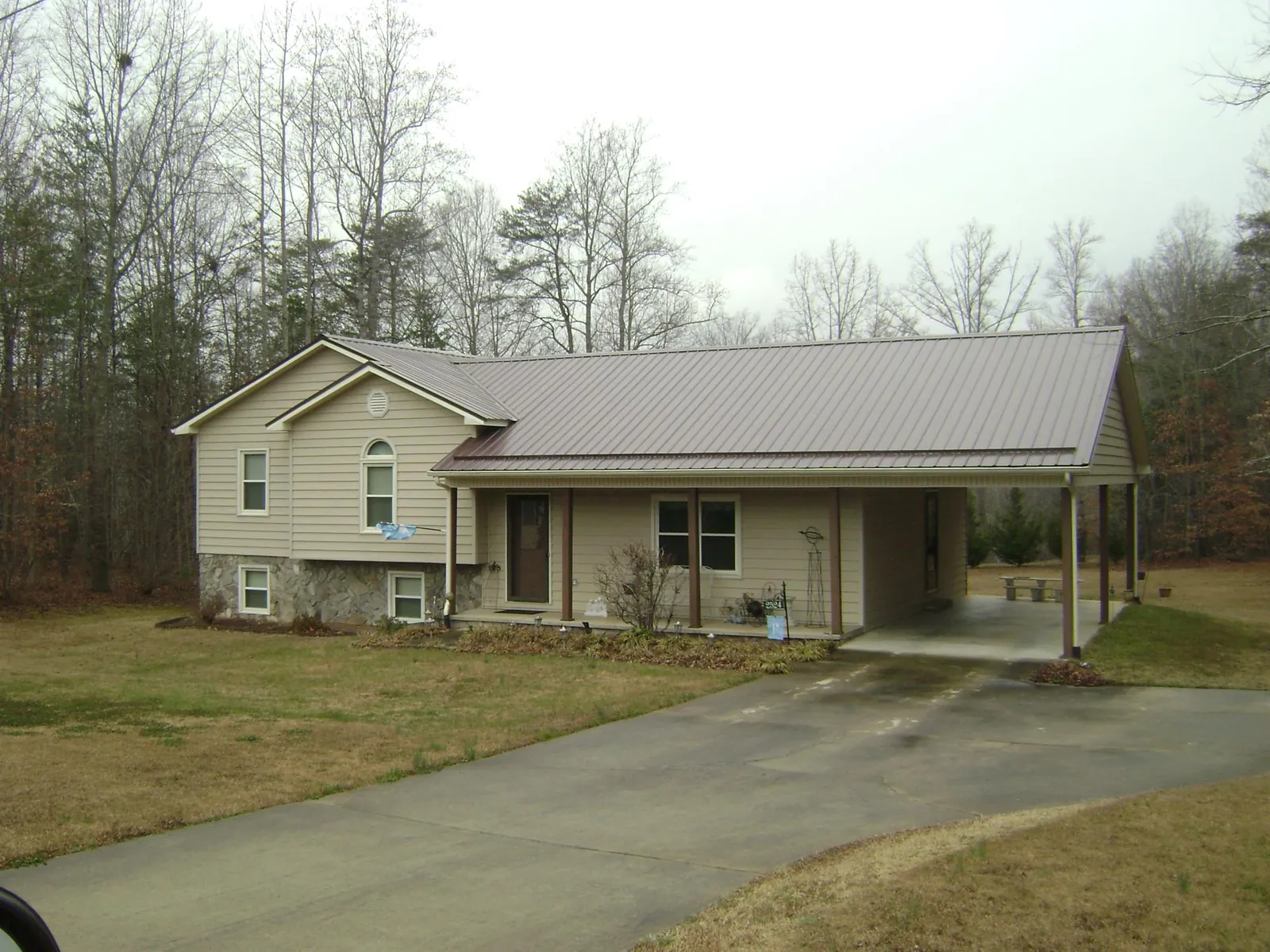 Brown metal roof on a tan split level home with an attached carport in North Sandwich