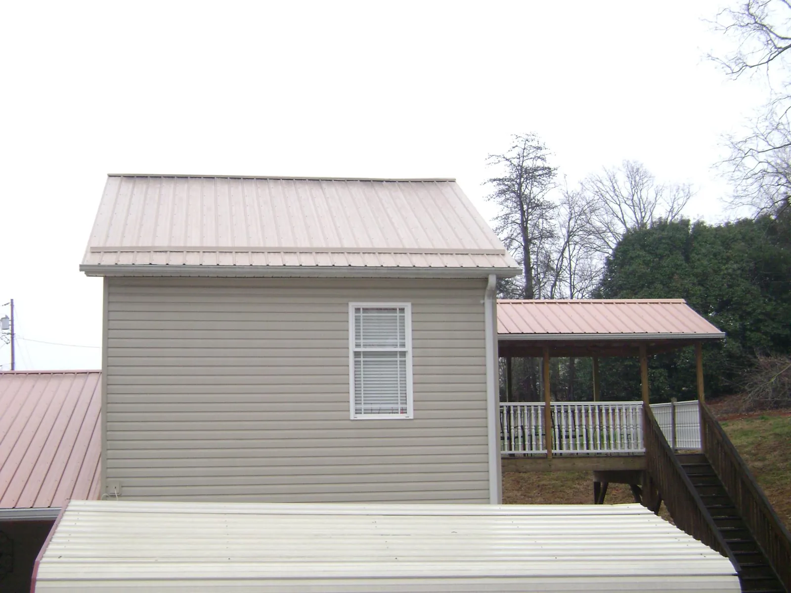 Tan metal roofs on a two story addition and attached porch, from a Roof Replacement job in North Sandwich